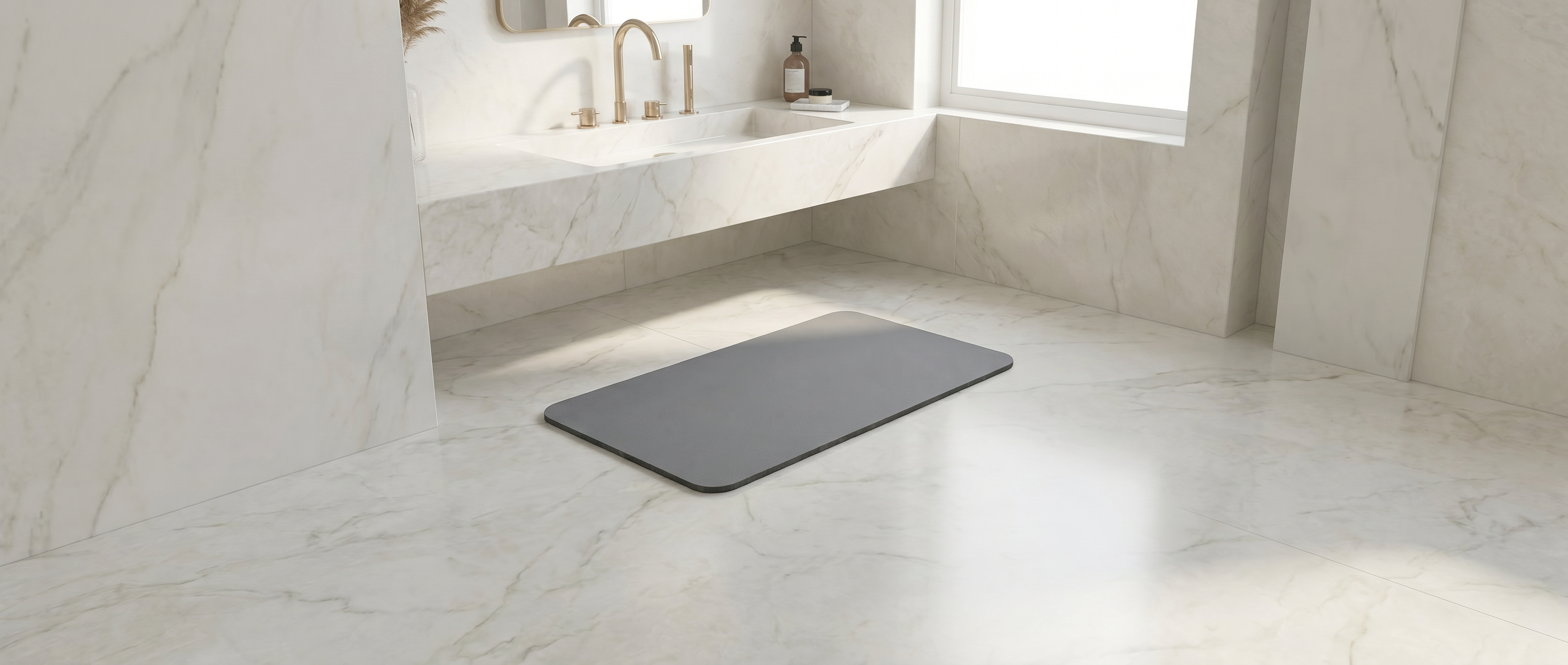 Tapis de bain en pierre de diatomite gris posé au sol dans une salle de bain en marbre avec robinetterie dorée