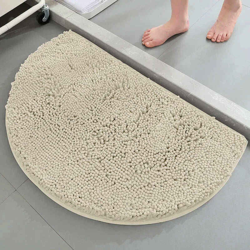 Pied nu devant un tapis de bain demi lune beige clair.