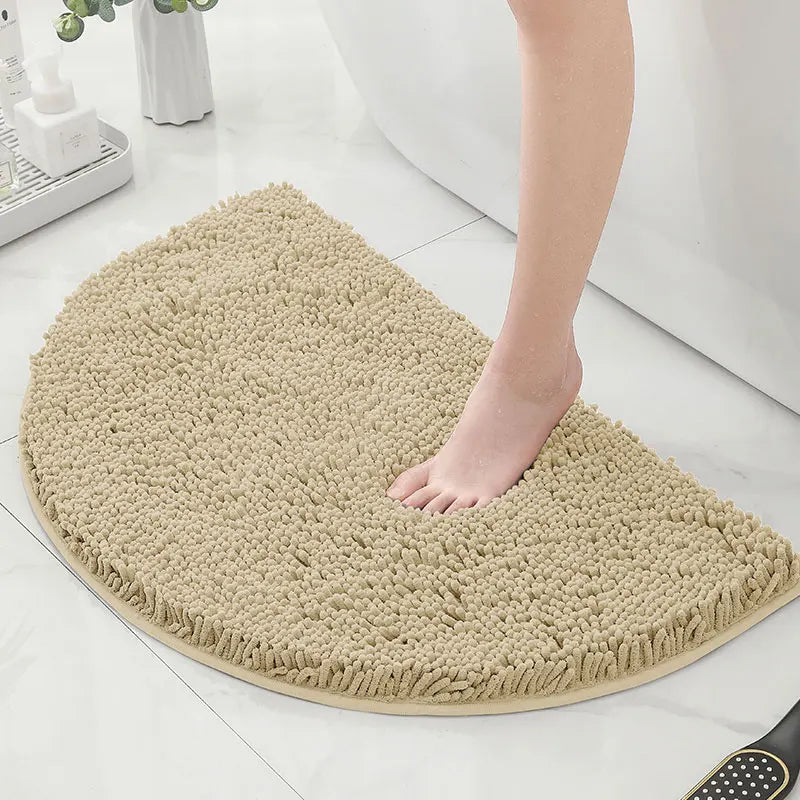 Pied nu marchant sur un tapis de bain demi lune beige.