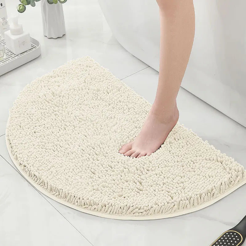 Pied nu marchant sur un tapis de bain demi lune blanc.