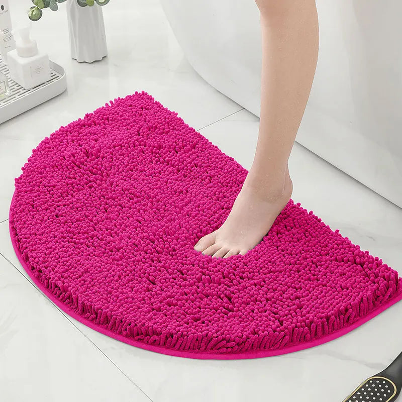 Pied nu marchant sur un tapis de bain demi lune rose.
