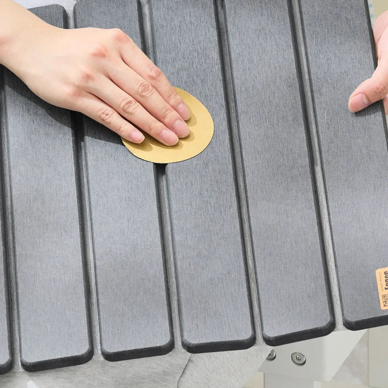 Main nettoyant la surface rainurée du tapis de bain gris avec une éponge.
