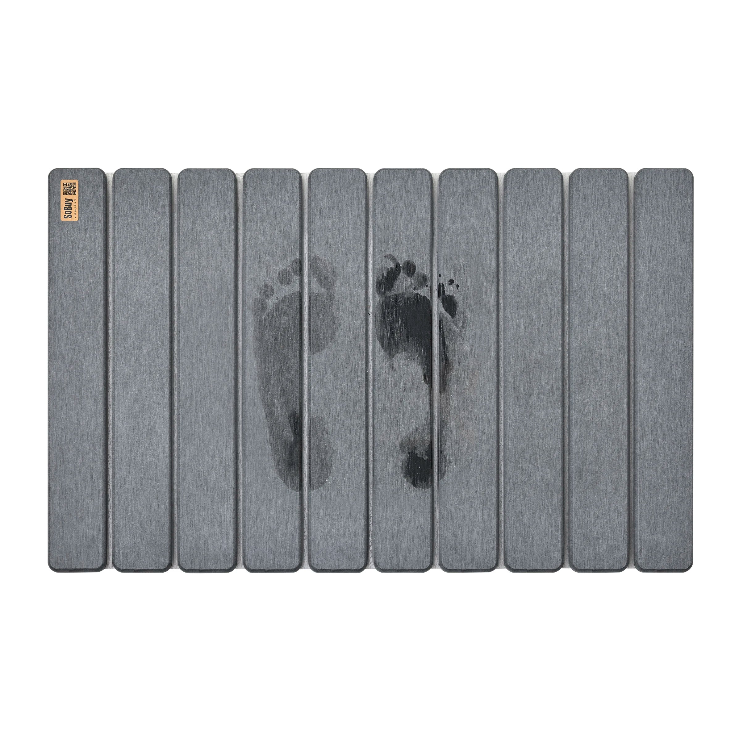 Tapis de bain gris foncé rainuré avec des traces de pas mouillées visibles sur la surface.