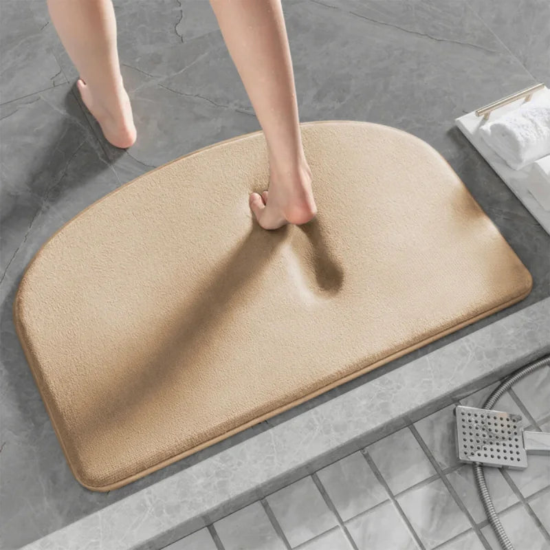 Pied nu marchant sur un tapis de bain gris à mémoire de forme beige.