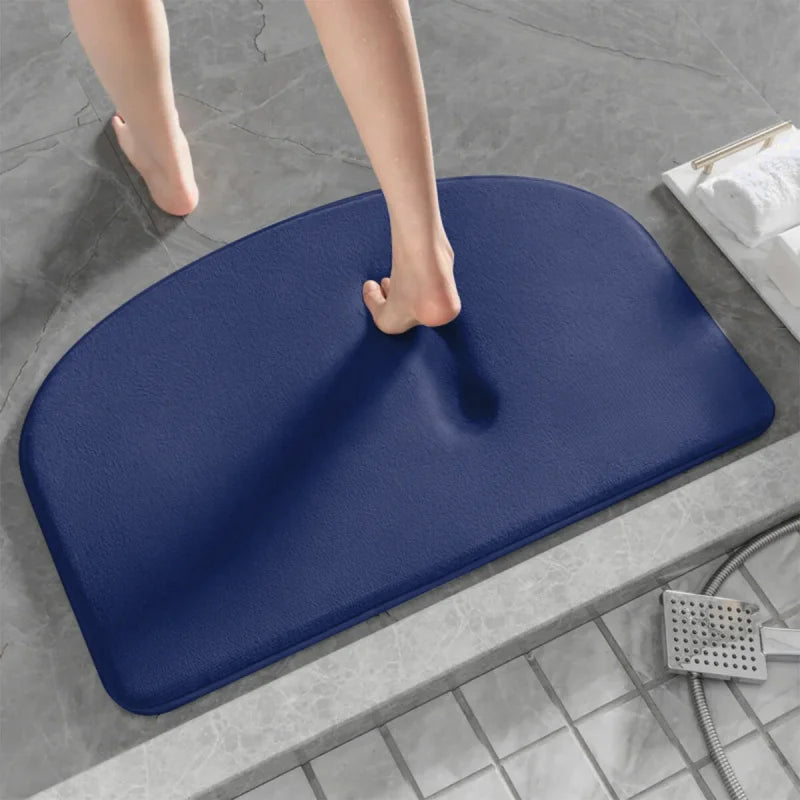 Pied nu marchant sur un tapis de bain gris à mémoire de forme bleu.