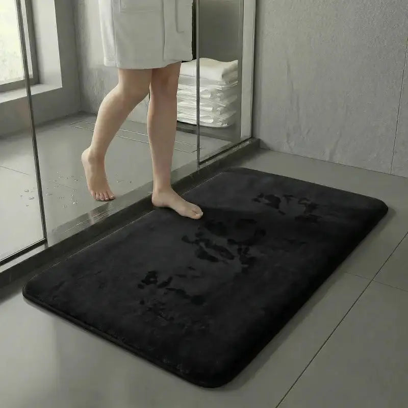 personne sortant de la douche posant le pied sur un tapis de bain noir absorbant avec traces d’humidité, salle de bain moderne