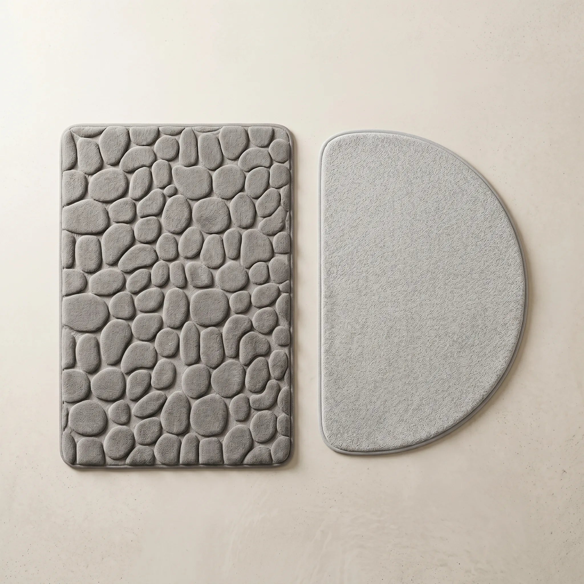 Duo tapis de bain antidérapant grande taille gris et tapis demi-cercle gris clair posés côte à côte sur fond crème.